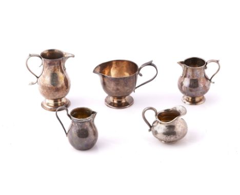 FIVE MOSTLY SILVER AND FOREIGN CREAM JUGS (5)To include the largest of baluster form, with a scrolling handle, raised on a ci