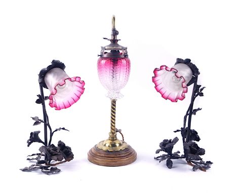 A PAIR OF PATINATED METAL LAMPS AND ANOTHER (3)Early 20th CenturyModelled as flowers with cranberry glass shades, 38cm high, 