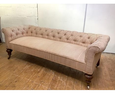 A country house three seat sofa, c. 1870, the low buttoned back and arms and padded seat in striped fabric of ticking type, r