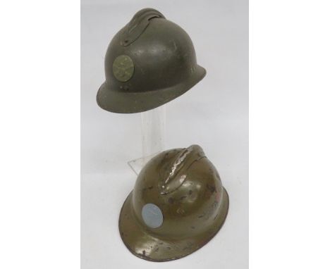 Two French M1926 Steel Helmets khaki green painted, one piece crown and brim. Top attached comb. One with Marine front badge,