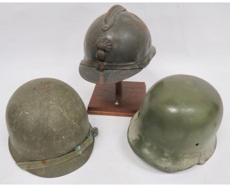 Three Various Steel Helmets consisting French M1915 steel helmet. Crown with comb. Lower brim with side seam. Leather chinstr