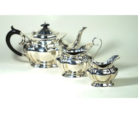 An Edwardian silver three piece tea service
Of ovoid form, with fluted and scalloped panels, the tea pot with an ebonised fin