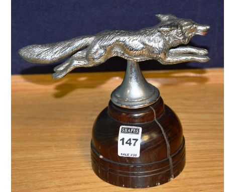 A vintage 'fox' car mascot raised on wooden stand, 18cm high
