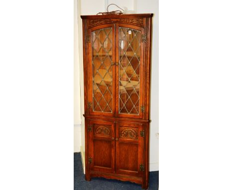 An Old Charm oak corner cabinet, with two leaded glazed doors above two panelled doors, light to interior, 66cm high x 68cm w