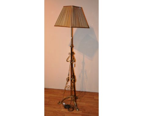 An Art nouveau brass adjustable floor lamp and shade, with stylized decoration, raised on scroll supports, 162cm high