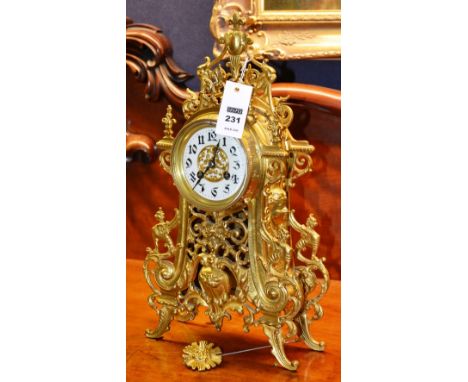 A French brass ornate mantel clock, the cream enamel dial with Arabic numerals, striking on bell movement to opposite, decora