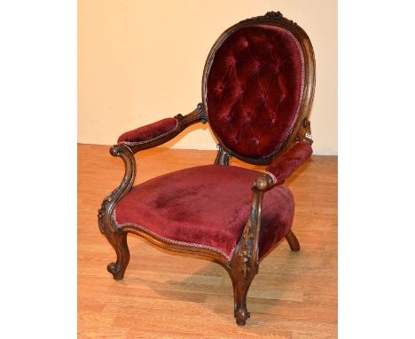 A Victorian mahogany framed ladies armchair, upholstered in later red velour, with button back, serpentine shaped seat, raise