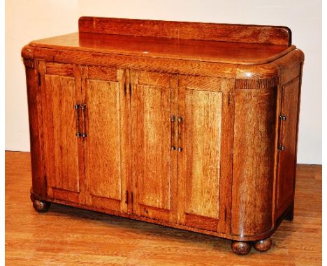 A vintage light oak sideboard, with two pairs of panelled doors, raised on ball feet, 99cm high x 138cm wide