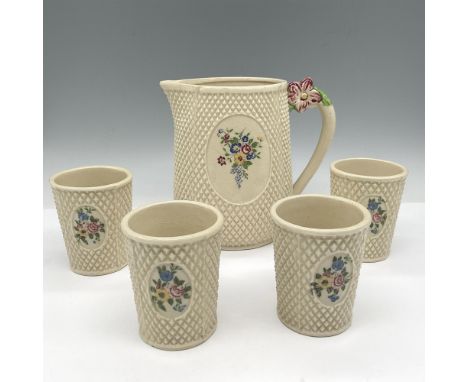 Cream colored pitcher and 4 glasses designed with textured exterior and oval floral motif, colored in blue, yellow and green.