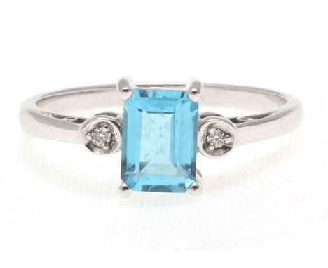 An emerald cut Blue Topaz carats sits between two round brilliant single white gold ring. This is a classic ring which will a