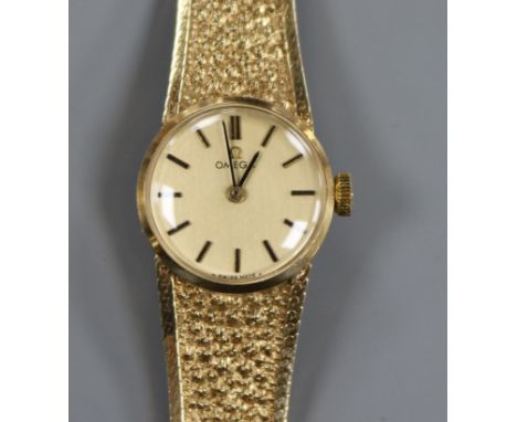 A lady's 9ct gold Omega manual wind wrist watch, on textured 9ct gold Omega bracelet.