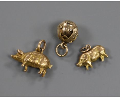 A yellow metal masonic ball pendant opening to form a cross and two yellow metal pig charms, one stamped 9ct gold.