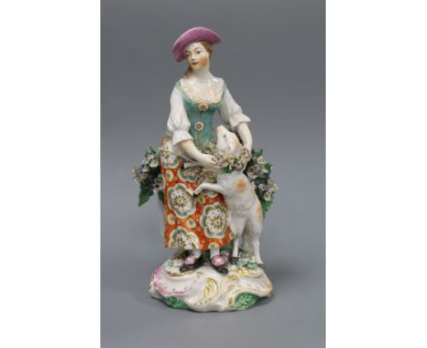A Derby figure of a shepherdess, c.1765, standing before bocage, holding a garland of flowers around a sheep, on a rococo scr