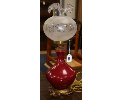 An oxblood red 19th century converted oil lamp and shade
