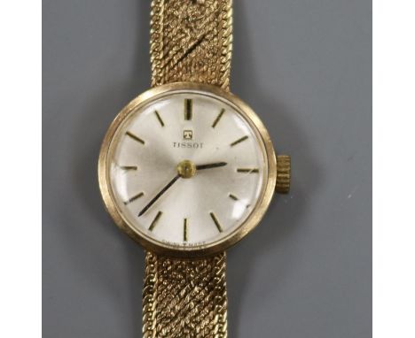 A lady's 9ct gold Tissot manual wind wrist watch on a textured 9ct gold bracelet.