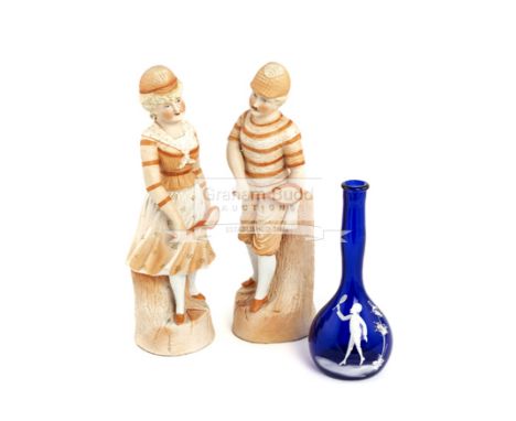 A pair of German bisque figures of tennis players, circa 1890modelled as a lady and gentleman tennis player standing, in a co