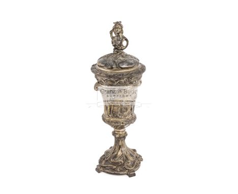 A Britannia metal sporting cup with cover, the foliate embossed cover with female finial, above a baluster cup two relief pan