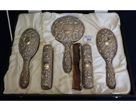 Cased silver ladies vanity set comprising; four brushes, hand mirror and a comb, all repousse decorated with foliage and grot