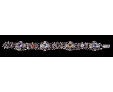 
	
		A multi gem set bracelet, the pierced scrolled panels set with circular cut gem stones including peridot, ruby and tourm