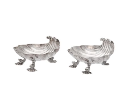 
	
		A pair of George II silver shell shaped butter dishes by Christian Hillan, London 1739, on three dolphin and shell feet,