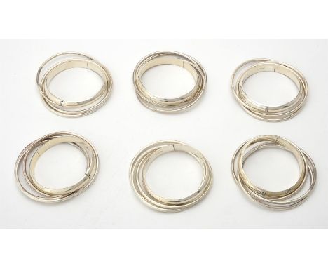 
	
		A collection of silver bangles, consisting of triple interlocking bangles and hinged bangles, with London hallmarks, app