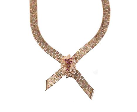 
	
		A 1970s 9 carat gold ruby necklace, the three colour brick links to a circular cut ruby set foliate panel, to a hexagona