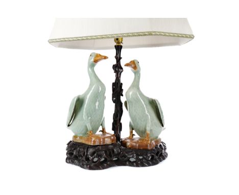 EARLY 20TH CENTURY CHINESE TABLE LAMP, modelled with a pair of ceramic geese in a celadon glaze, on a carved wood stand, the 