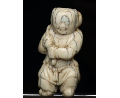 An Antique Japanese Ivory Netsuke, [CITES] in the form of a man carrying a burden, age cracks and old surface wear, 5.8cm lon