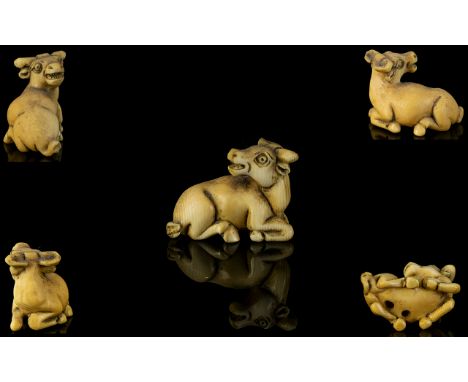 Japanese Early 19th Century Nice Quality And Signed Carved Ivory Netsuke in the form of a horned and hoofed animal in a sitti