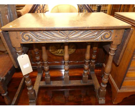 A joined oak dropflap low occasional table, having a carved frieze, raised on turned and square cut supports, w.64cm (flaps d