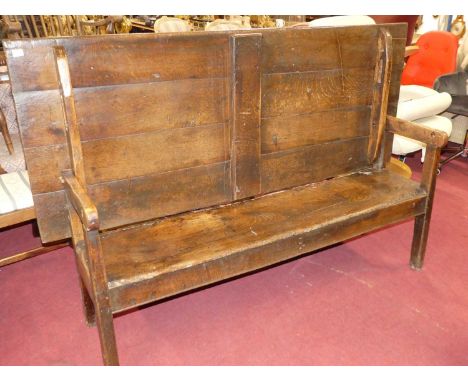 An antique joined oak and elm long bench settle, having a fold-over top, length 181cmSome losses and general wear throughout.