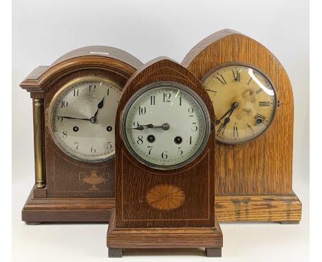 An Edwardian inlaid oak Gothic mantel clock, having unsigned convex white enamel dial, h.30cm; together with one other simila