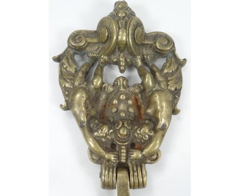 A rococo design brass door knocker, of shaped outline set with two cherubs, on a scroll base, with screw back, 22cm high and 
