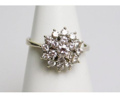 A diamond floral cluster ring, with three rows of round brilliant cut diamonds, in claw setting, on white metal, with rubbed 