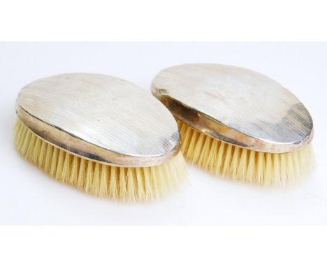 A pair of George V silver backed clothes brushes, of oval engine turned outline, each with an initialled cartouche, Birmingha