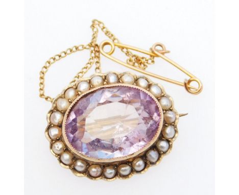 A late Victorian brooch, of oval outline, set with an amethyst coloured stone with seed pearl surround, plain pin and chain b