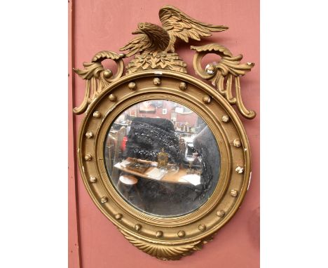 A Regency gilt framed wall mirror with eagle finial above circular main section.