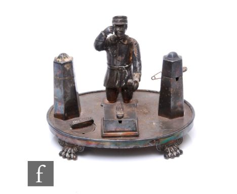 An early 20th Century silver plated cruet set modelled as a boot boy flanked by salt and pepper bollards and a mustard pot to