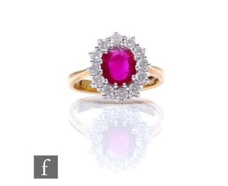 An 18ct ruby and white sapphire cluster ring, central oval ruby, length 8mm, within a border of twelve brilliant cut white sa