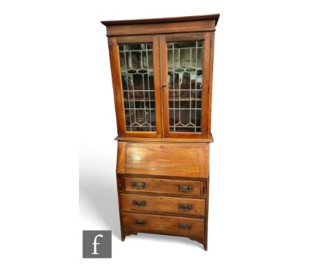 An Edwardian crossbanded mahogany bureau bookcase enclosed by a pair of coloured leaded light doors above a fitted interior a