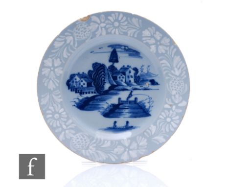 An 18th Century English Bristol Delftware pottery plate circa 1750, the central well decorated in blue with a lake scene with