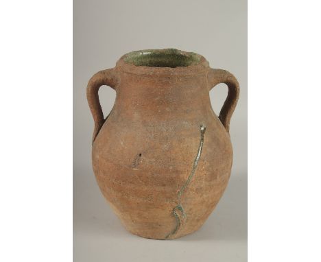 A 10TH CENTURY MIDDLE EASTERN UNGLAZED POTTERY TWIN HANDLE JUG, the interior with traces of green glaze, 22.5cm high.