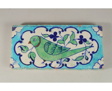 A RARE EARLY 19TH CENTURY NORTH INDIAN MULTAN POTTERY TILE, depicting a green parrot, 30cm x 15cm.