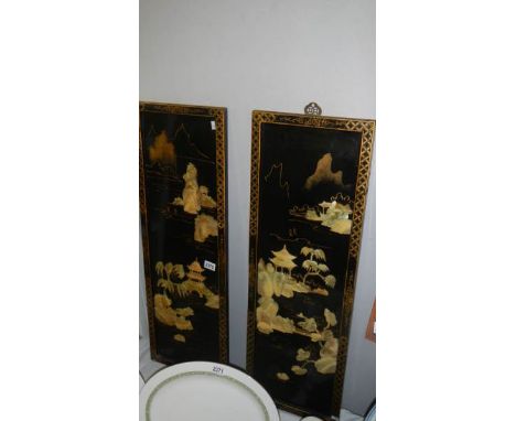 A pair of Japanese lacquered panels with mother of pearl figures.