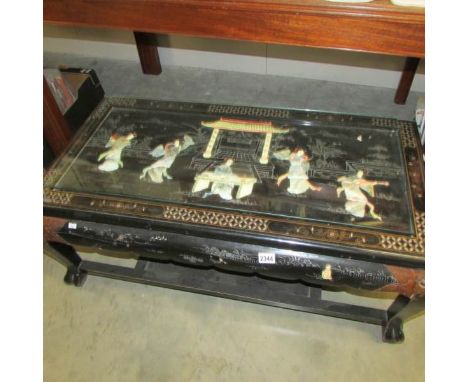 A black coffee table decorated with mother of pearl figures.