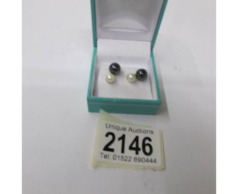 A pair of gold set cultured pearl earrings in black and white pearls.