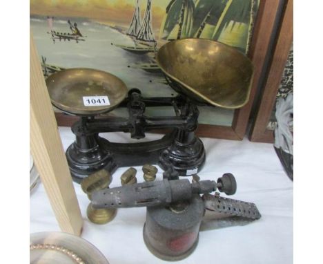 A set of kitchen scales with weights and a blow lamp.
