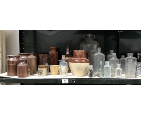 A shelf of stoneware jugs, pots and jars with some vintage glass bottles (some with raised script "Boots" etc)