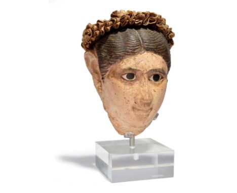 An Egyptian stucco painted head of a woman Roman Period, circa late 1st - early 2nd century AD with her face painted a natura