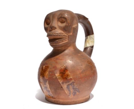 A Moche stirrup vessel Peru, circa 100 - 600 AD pottery with a skull top and with painted cloak outline, arms and hands, 19cm